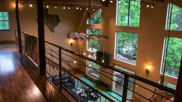 A spacious interior with a wooden floor, a balcony with a railing, and large windows with natural light. - Riverfront Cabins  and  Vacation Homes (Rio Frio)
