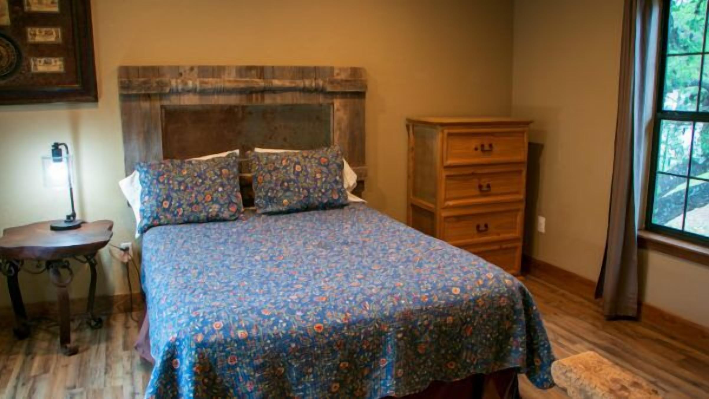 Un dormitorio con cama, cómoda, mesita de noche y ventana.