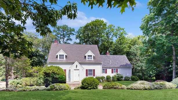 A two-story house with a front porch, a well-maintained lawn, and mature trees in the background. - West Falmouth Family Retreat Near Chapoquoit Beach (Falmouth)