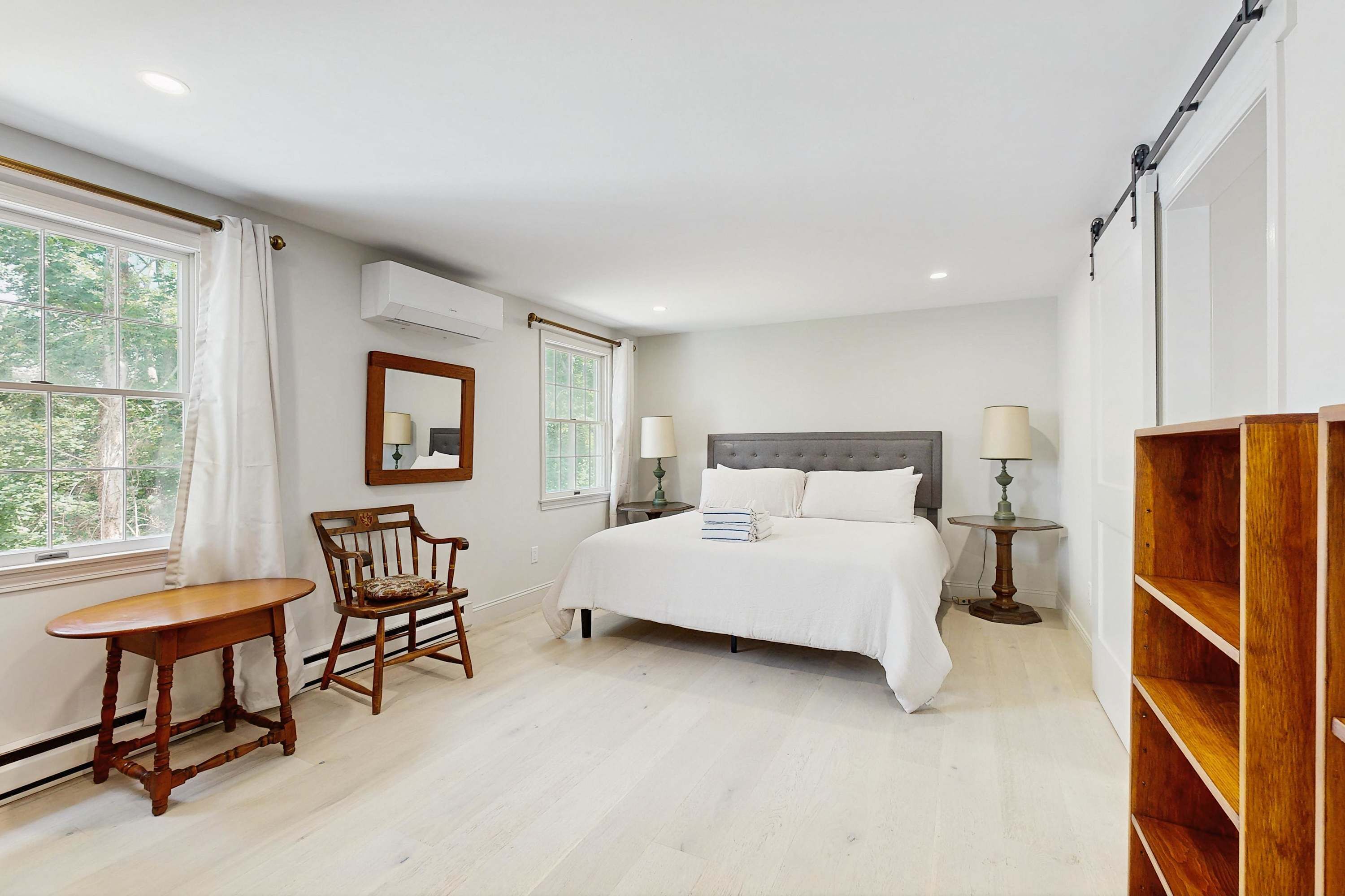 A bedroom with a bed, a chair, a table, and a bookshelf.