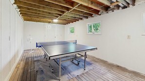 A ping pong table in a room with wooden beams, white walls, and a fan. - West Falmouth Family Retreat Near Chapoquoit Beach (Falmouth)