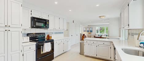A modern kitchen with white cabinetry, a black stove, and a stainless steel sink.