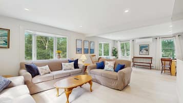 A spacious living area with two sofas, a coffee table, and a dining table.