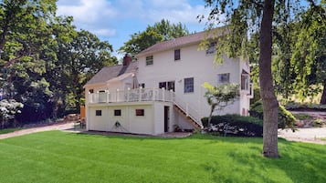 Une maison à deux étages avec un porche à l’avant, un petit garage attenant et une pelouse bien entretenue.