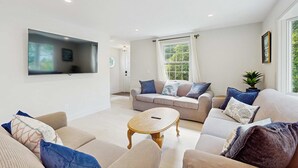 A living room with a sofa set, a coffee table, and a TV mounted on the wall. - West Falmouth Family Retreat Near Chapoquoit Beach (Falmouth)