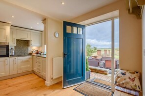 A modern kitchen with white cabinets, a granite countertop, and a blue door leading to a balcony with outdoor furniture. - 2 Bed in Newark (oc-91051) (Caunton)