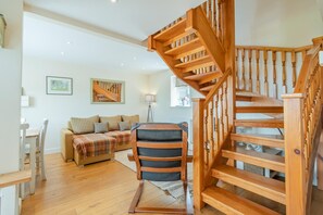 A wooden staircase with a modern design, a sofa with a plaid blanket, and a dining area with a table and chairs. - 2 Bed in Newark (oc-91051) (Caunton)