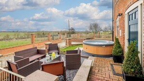 Eine Terrasse im Freien mit Korbmöbeln, einem Whirlpool und Blick auf die Landschaft.