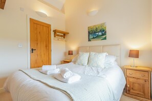 A bedroom with a large bed, two bedside tables with lamps, a wooden door, and a painting on the wall. - 2 Bed in Newark (oc-91051) (Caunton)