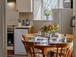 A kitchen with a dining table set for four, a coffee maker, a kettle, and a refrigerator. - 3 Bed in Cosheston (oc-90732) (Cosheston)