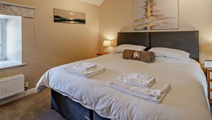 A neatly made bed with towels, a nightstand with a lamp, a window with a view, and two paintings on the wall. - 3 Bed in Cosheston (oc-90732) (Cosheston)