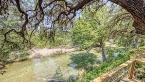 A wooden deck overlooking a clear stream with surrounding trees. - Riverfront Cabins  and  Vacation Homes (Rio Frio)