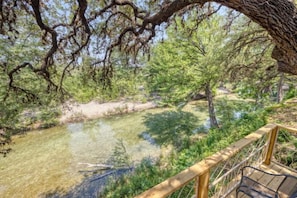 A wooden deck overlooking a clear stream with surrounding trees. - Riverfront Cabins  and  Vacation Homes (Rio Frio)