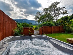 A hot tub in a backyard with a wooden fence, greenery, and a tree. - 1 Bed in Llangollen (oc-91040) (Llangollen)