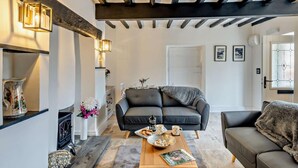 Ein Wohnzimmer mit einer Couch, einem Couchtisch mit Zeitschriften, einem Kamin und einer Treppe.