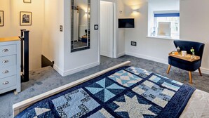 Ein Schlafzimmer mit Bett, Kommode, Spiegel, Fernseher, Fenster mit Blick und Nachttisch mit Tablett.