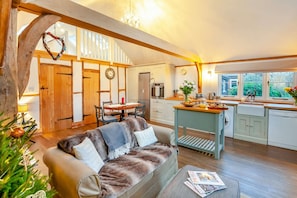A cozy living room with a sofa, a dining table, and a kitchen area with a sink and cabinets.
