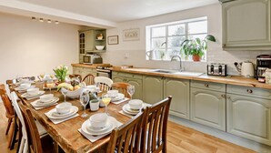 A kitchen with a dining table set for six, a window with a view, and light green cabinetry.