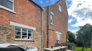 A brick house with a window, a chimney, and a garden.