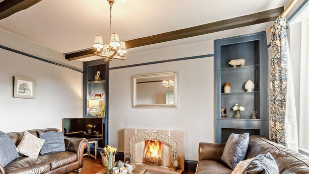 A living room with a fireplace, leather sofas, a coffee table, and a chandelier.