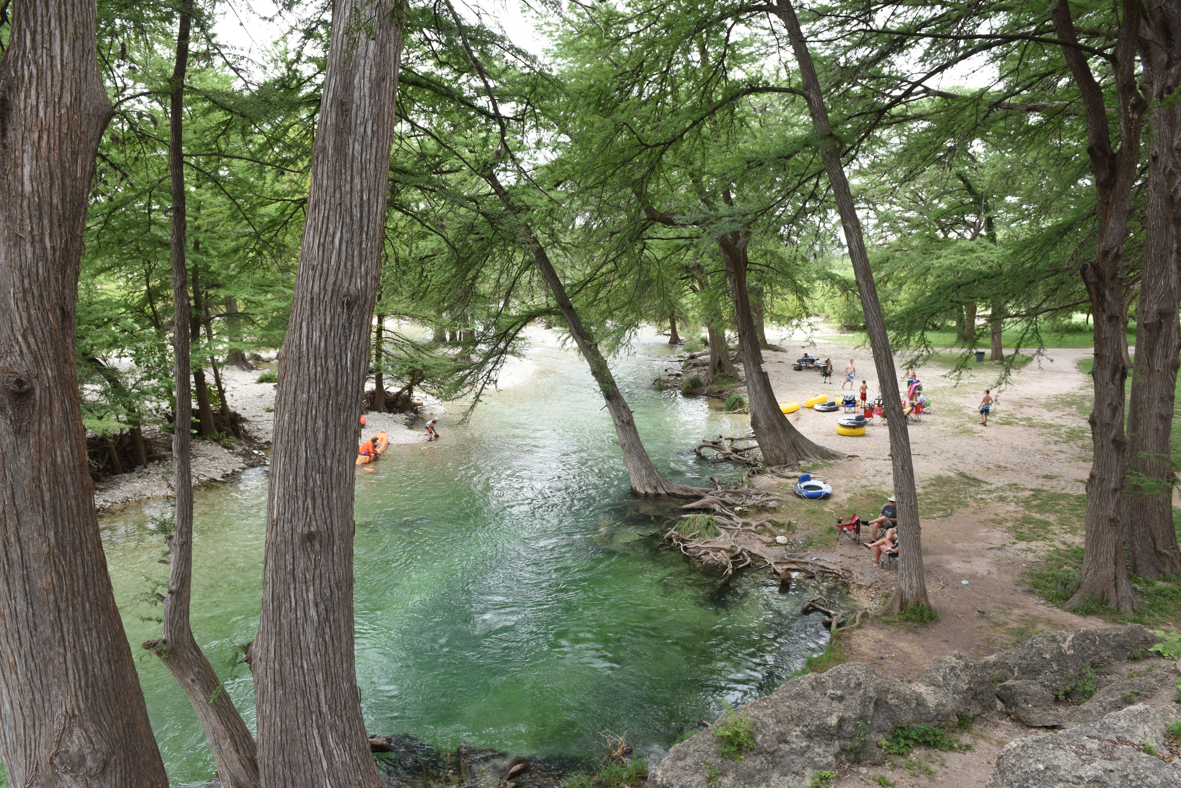 A river surrounded by trees with people engaging in water activities.