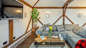 A cozy living room with a sofa, a coffee table, a TV, and a plant. - 1 Bed in Northwich (oc-91435) (Northwich)