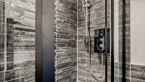 A modern shower with a handheld showerhead, a control panel, and a glass door. - 1 Bed in Northwich (oc-91435) (Northwich)