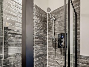 A modern shower with a handheld showerhead, a control panel, and a glass door. - 1 Bed in Northwich (oc-91435) (Northwich)