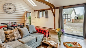 A cozy living room with a grey sofa, a wooden coffee table, and a large window with curtains. - 1 Bed in Northwich (oc-91435) (Northwich)