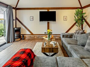 A cozy living room with a fireplace, a sofa, a coffee table with flowers, and a television on the wall. - 1 Bed in Northwich (oc-91435) (Northwich)