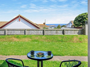 A round table with a glass top and two chairs, a small plate with cookies, and two black mugs on the table. - 2 Bed in Brixham (oc-91427) (Brixham)