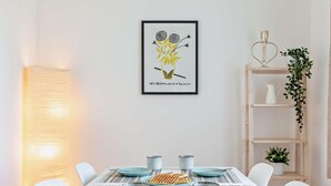 A dining table with a waffle, plates, and mugs, a framed artwork above it, and a white chair. - 2 Bed in Brixham (oc-91427) (Brixham)