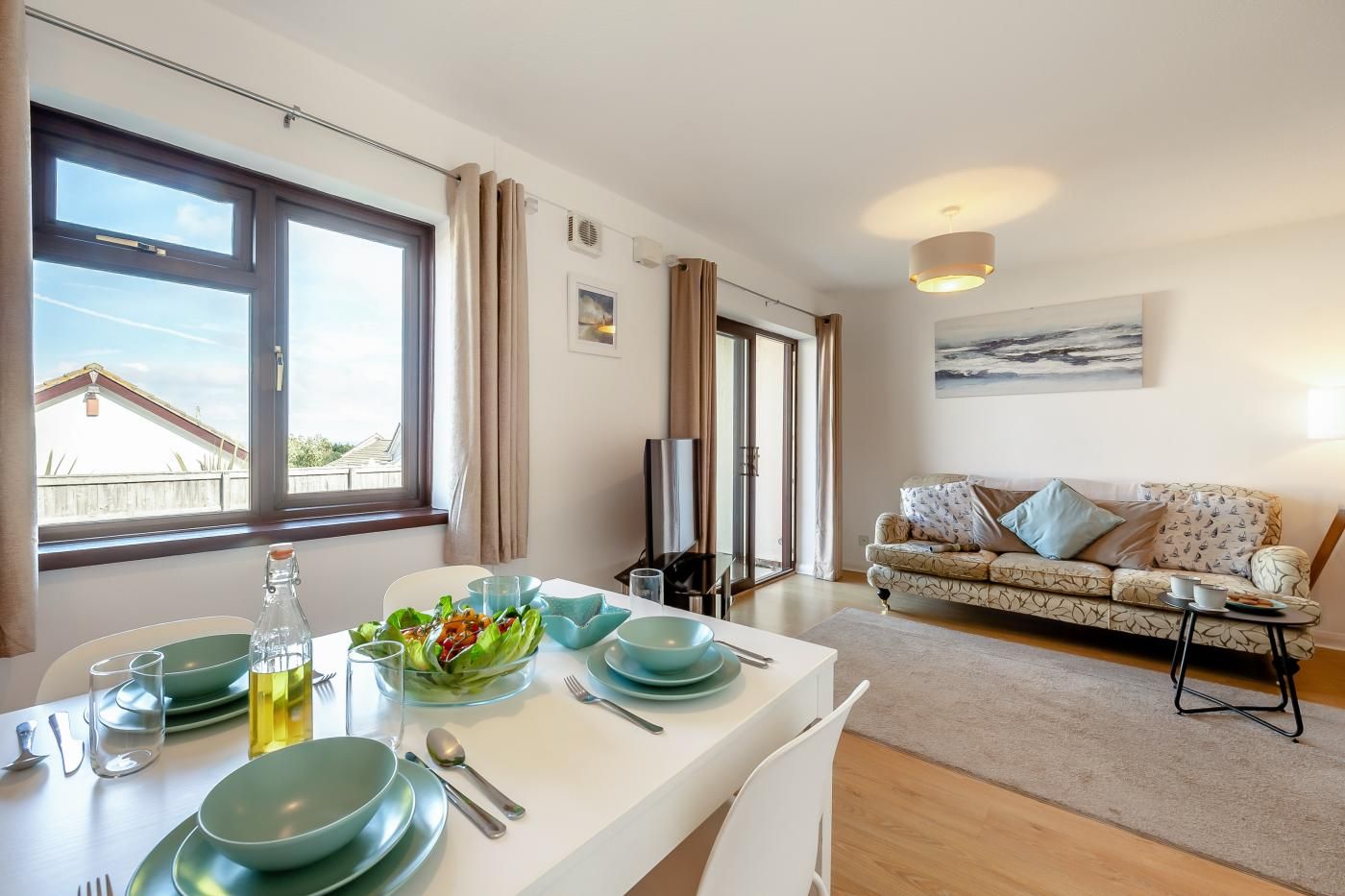 A dining area with a table set for four, a sofa, and a TV in the background.