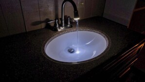 A bathroom sink with a faucet, a mirror above it, and a wall outlet. - Riverfront Cabins  and  Vacation Homes (Rio Frio)