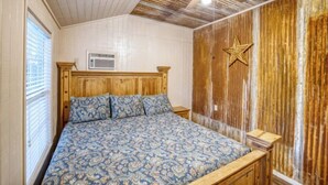 A bedroom with a wooden bed, a ceiling fan, and a star decoration on the wall. - Riverfront Cabins  and  Vacation Homes (Rio Frio)