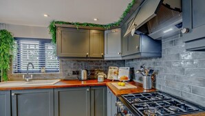Uma cozinha moderna com armários escuros, um fogão de aço inoxidável e uma janela com persianas.