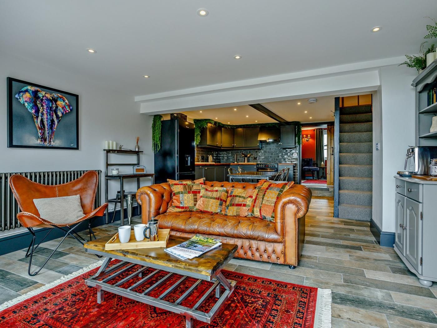 A living room with a leather sofa, a coffee table, and a red patterned rug.