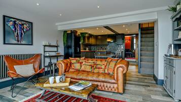 A living room with a leather sofa, a coffee table, and a red patterned rug.