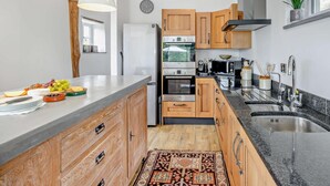 Une cuisine moderne avec des meubles en bois, des appareils électroménagers en acier inoxydable et un plan de travail en marbre.