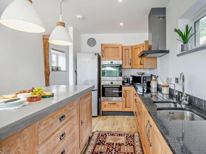 Eine moderne Küche mit Holzausstattung, Edelstahlgeräten und einer Marmorarbeitsplatte.