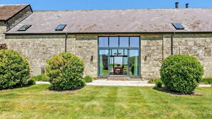 A stone building with a large glass entrance, a sloped roof, and two small trees in the front yard. - 4 Bed in Shaftesbury (oc-91456) (East Melbury)