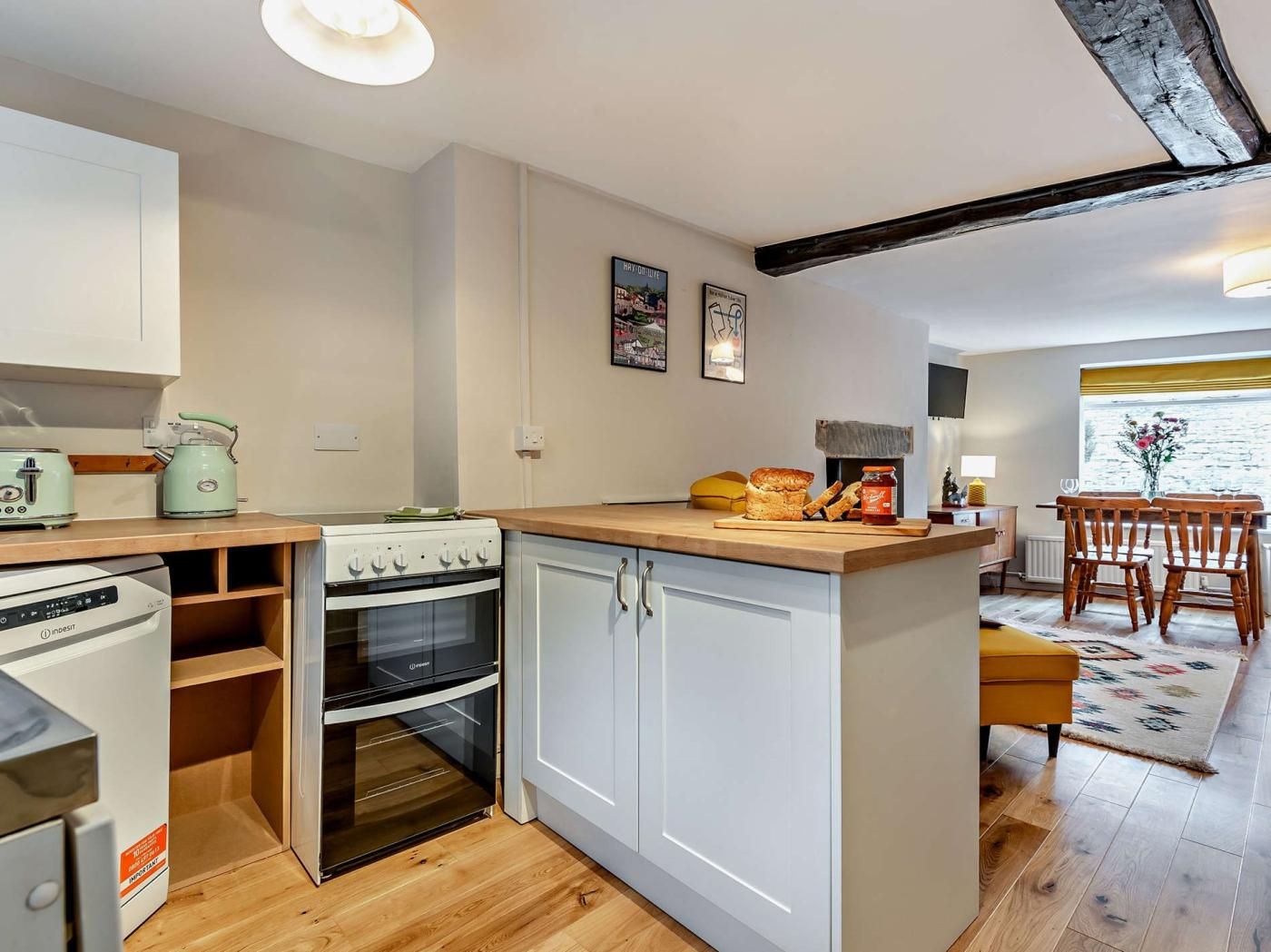 A compact kitchen with a stove, oven, and a small dining area with wooden chairs and a table.