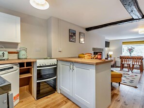 A compact kitchen with a stove, oven, and a small dining area with wooden chairs and a table.