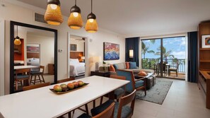 Habitación de hotel con comedor, sofá, balcón con vistas y un cuadro en la pared.
