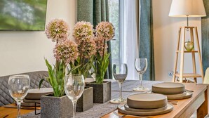 Uma mesa de jantar posta com pratos, copos e um vaso de flores.