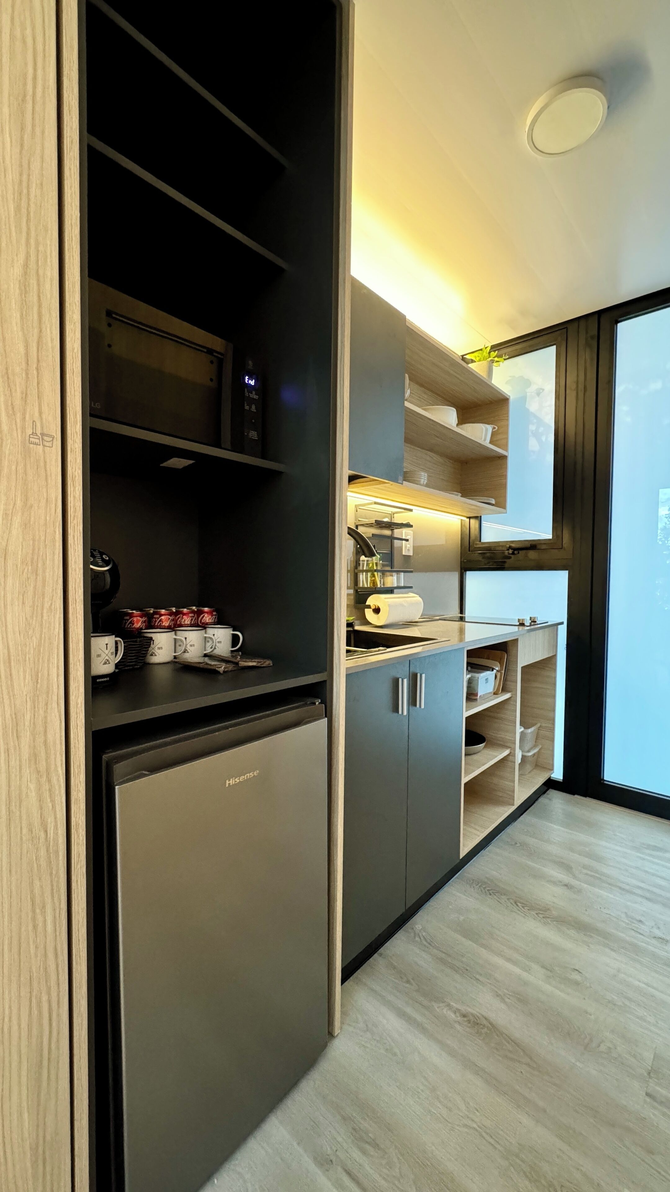 Una cocina moderna con microondas integrado, refrigerador y cafetera.