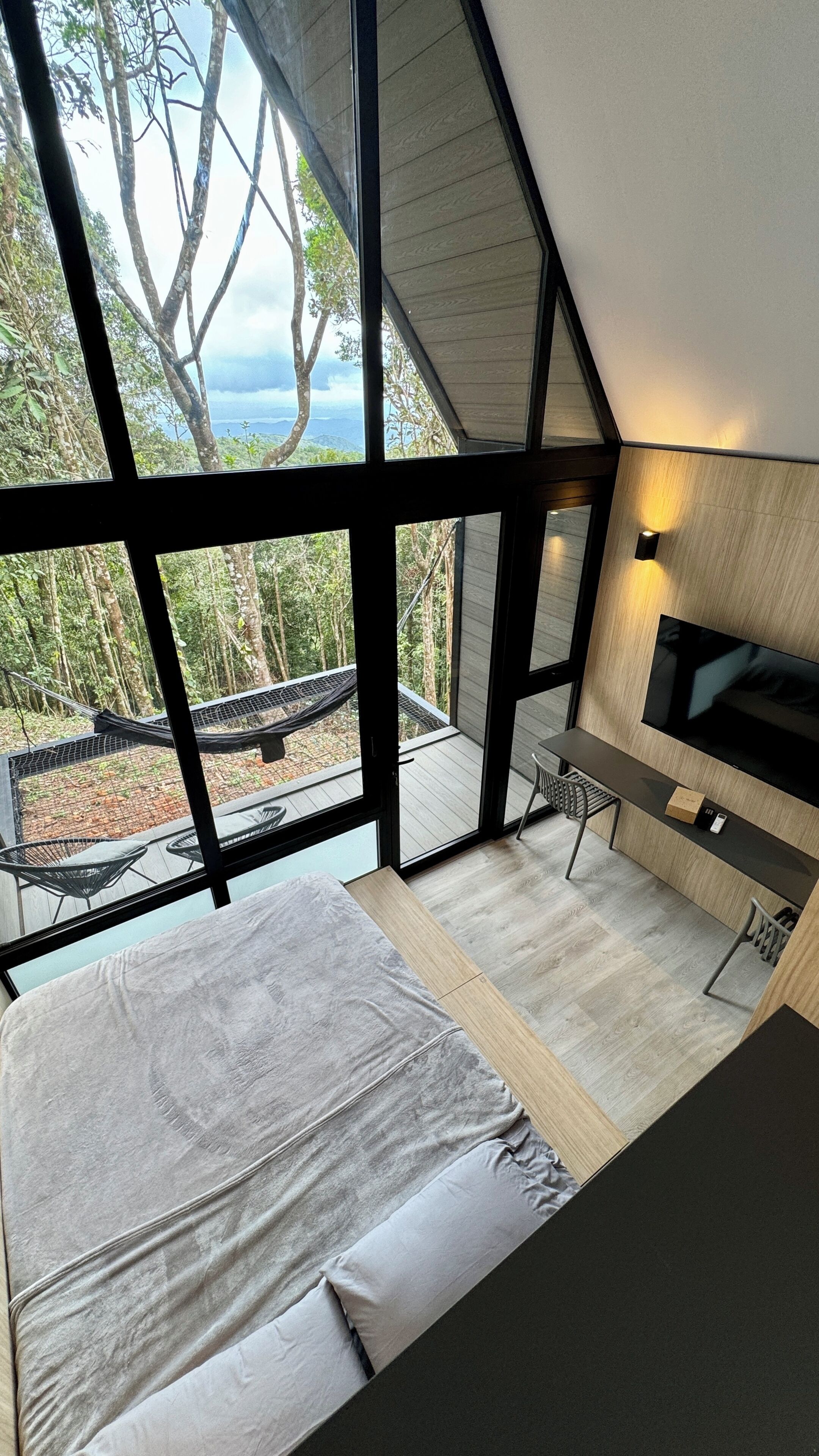 Un dormitorio con una cama grande, televisor y vista al exterior.