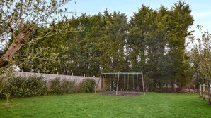 Ein grüner Hinterhof mit Schaukel und Holzzaun.