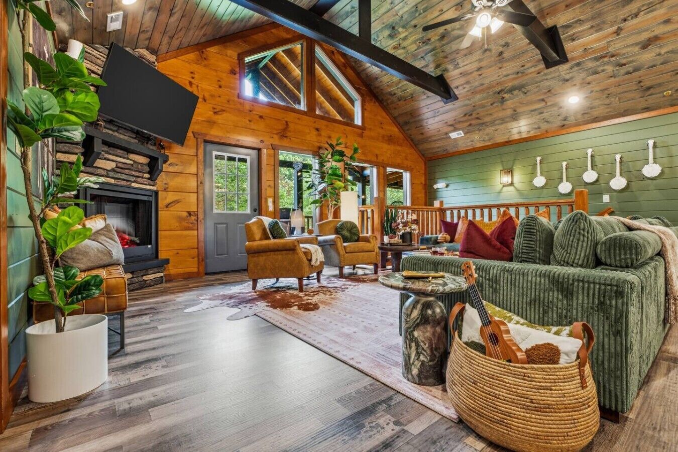 A cozy cabin interior with a fireplace, wooden walls, a green couch, and a stone fireplace surround.