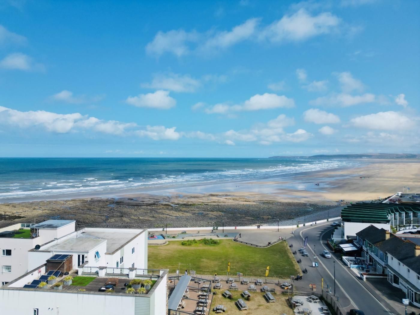 Een kustplaatsje met een strand, gebouwen en een weg.